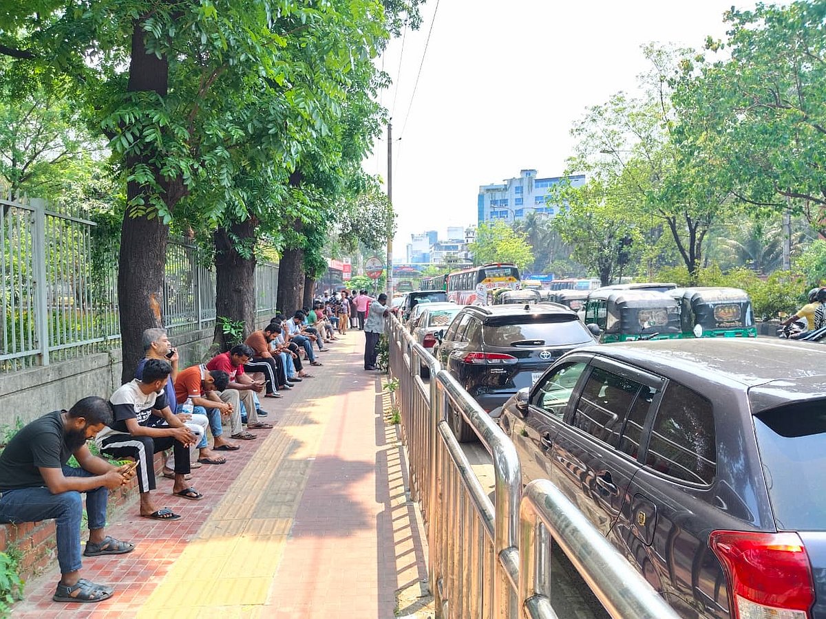 দীর্ঘ অপেক্ষায় ক্লান্ত হয়ে রাস্তার পাশের ফুটপাতে গাছের ছায়ায় অপেক্ষা করছেন শহীদুল ইসলাম ( প্রথমজন) ও অন্য চালকেরা। আজ শুক্রবার দুপুর সোয়া ১২টার দিকে রাজধানীর আসাদগেটের তালুকদার ফিলিং স্টেশনের পাশে