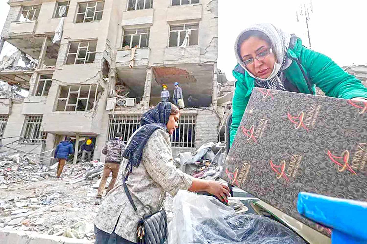 বোমায় বিধ্বস্ত ভবন থেকে জিনিসপত্র নিয়ে যাচ্ছে ইরানি পরিবার