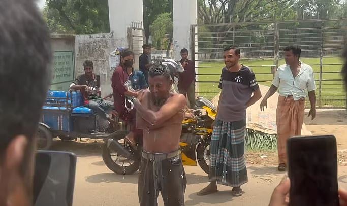 মহীপুর সরকারি কলেজের মূল ফটকের সামনে দাঁড়িয়ে নিজের গায়ে দুধ ঢেলে গোসল করেন জাহিদুল ইসলাম