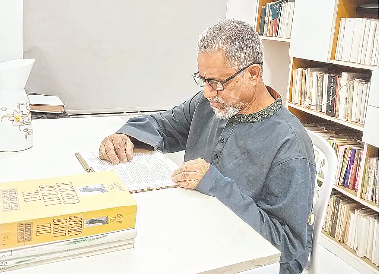 নিজের বাড়ির গ্রন্থাগারে বই পড়ছেন আমজাদুল হোসেন। ঢাকার বাসাবো এলাকায়
