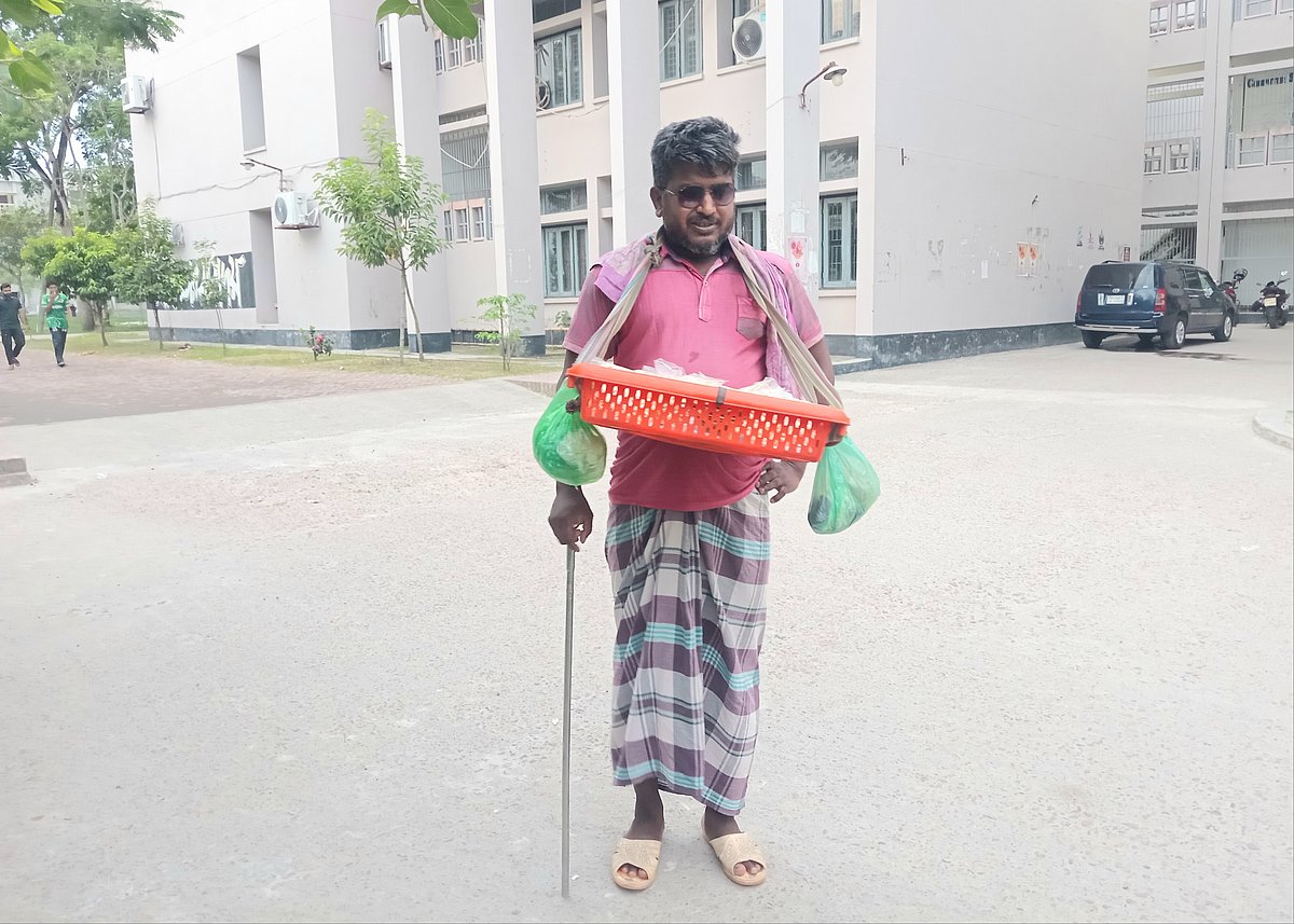 খুলনা বিশ্ববিদ্যালয় ক্যাম্পাসে ছোট প্লাস্টিকের ঝুড়িতে করে বাদাম, বুট, পপকর্ন বিক্রি করেন গোলাম মোস্তফা। সোমবার বিকেলে বিশ্ববিদ্যালয়ের একাডেমিক ভবন-১–এর সামনে তোলা