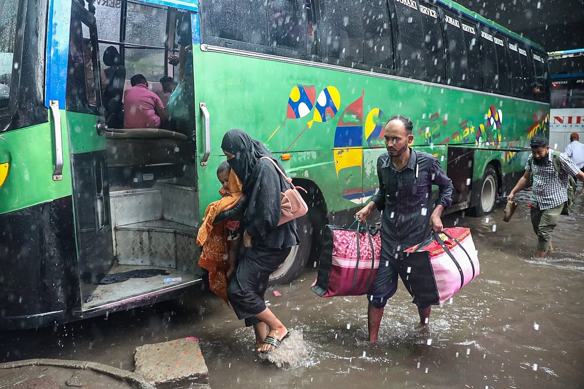 কাউন্টারের সামনের সড়কে হাঁটুসমান পানি জমে গেছে। এর মধ্যে দিয়েই বাসে উঠছেন ঘরমুখো যাত্রীরা। আজ মঙ্গলবার সকালে, সায়েদাবাদ, ঢাকা  