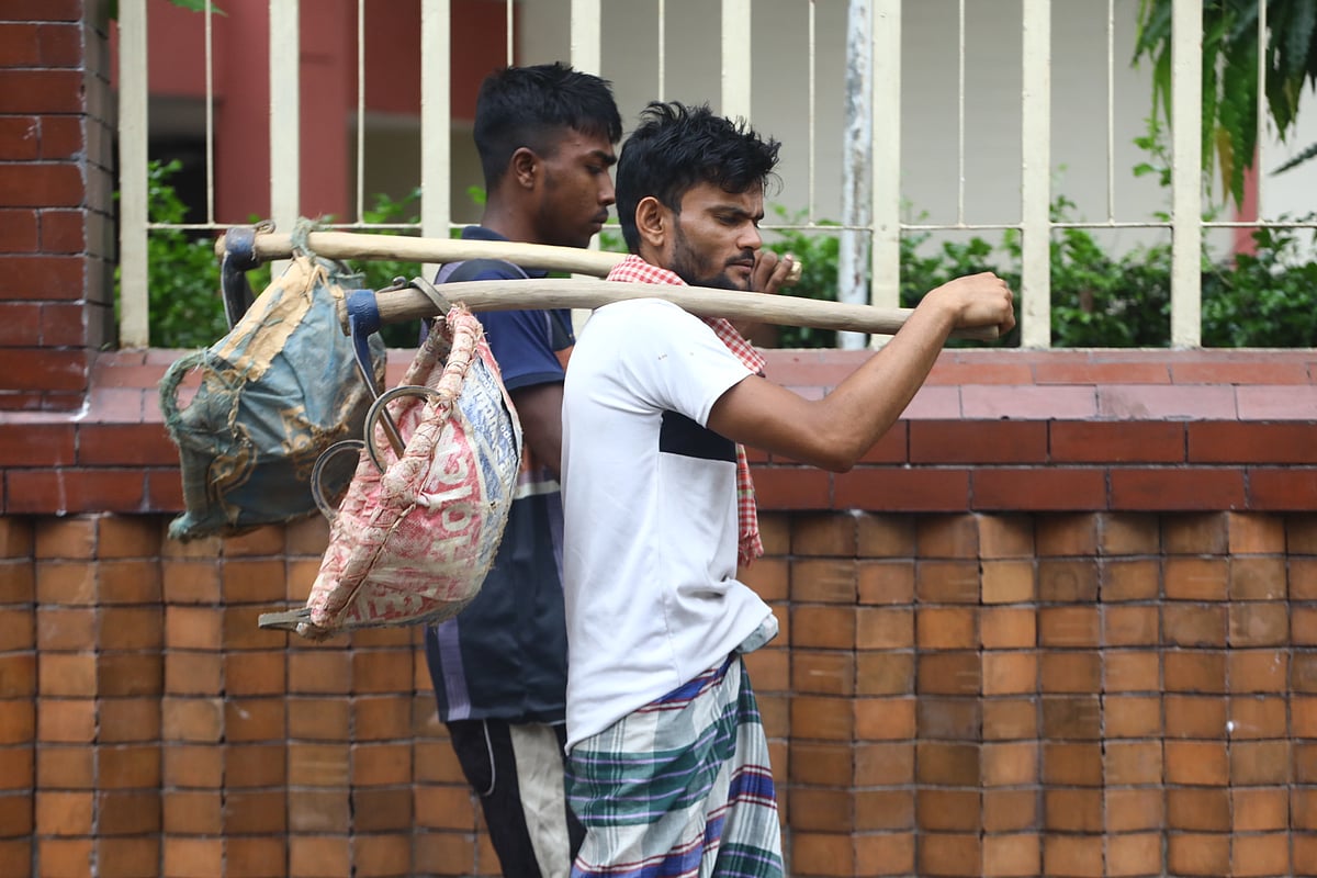 মাটি কাটার কোদাল ও টুকরি নিয়ে কাজের খোঁজে বেরিয়েছেন দুই শ্রমিক। বন্দরবাজার, সিলেট