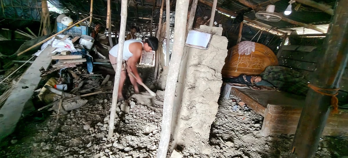ঘরে ধসে পড়া দেয়ালের মাটি কোদাল দিয়ে সরাচ্ছেন আবদুল কাদের। আজ সকালে চট্টগ্রামের বাঁশখালী উপজেলার শেখেরখীল ইউনিয়নের বোচারপাড়ায়