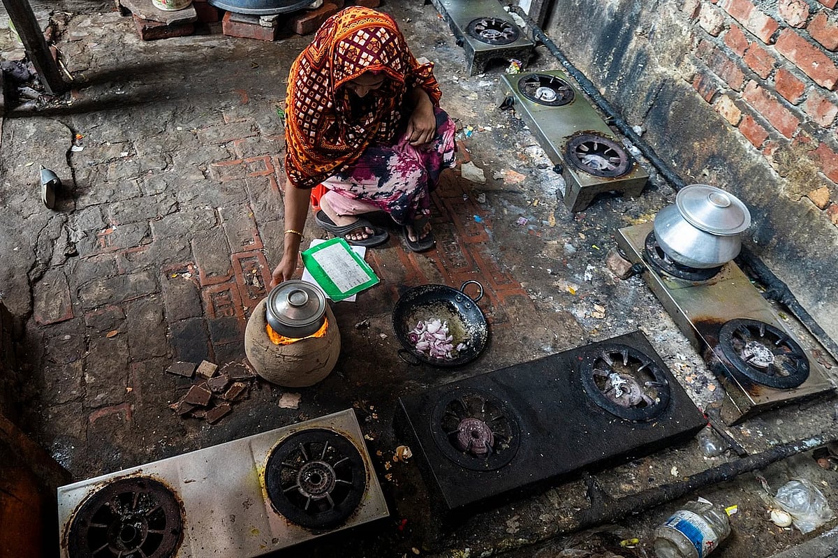 রান্নাঘরে গ্যাসের চুলা আছে, কিন্তু গ্যাস নেই। তাই মাটির চুলায় রান্না করছেন এই নারী