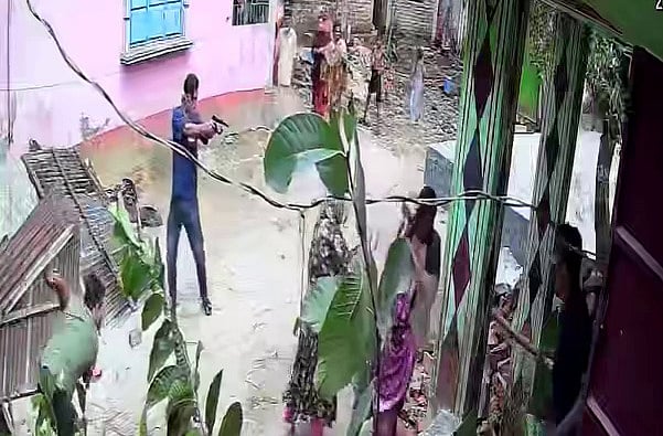 ঘরের সামনে কয়েকজন নারী। তাঁদের দিকে অস্ত্র তাক করে আছেন মুখোশ পরা যুবক। গতকাল নোয়াখালীল বেগমগঞ্জে