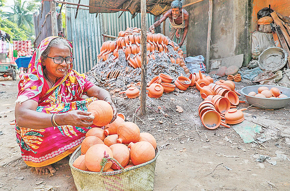 বাজারে নিয়ে আসার জন্য মাটির পণ্য ঝুড়িতে সাজাচ্ছেন এক নারী