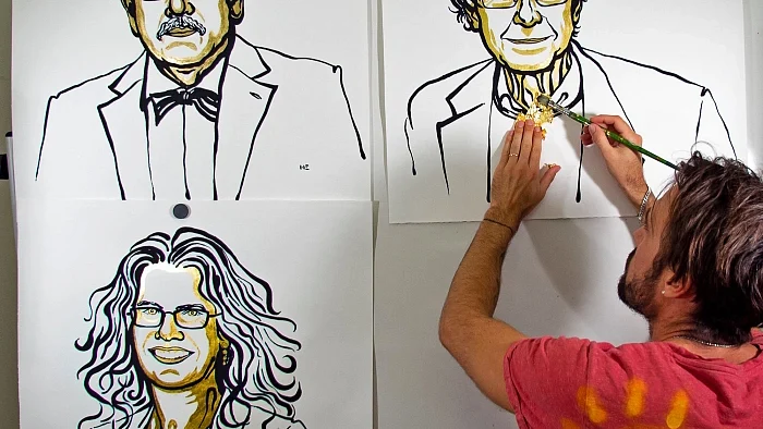 Niklas Elmehed attaches gold foil to the portrait of Sir Roger Penrose who won the the 2020 Nobel Prize for physics