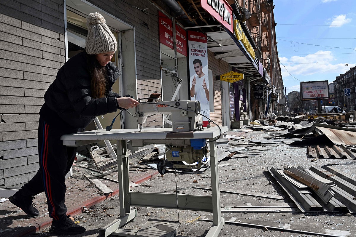 A woman checks a sewing machine outside her atelier damaged by shelling amid Russian invasion of Ukraine in Kyiv on 17 March 2022, as Russian troops try to encircle the Ukrainian capital as part of their slow-moving offensive.