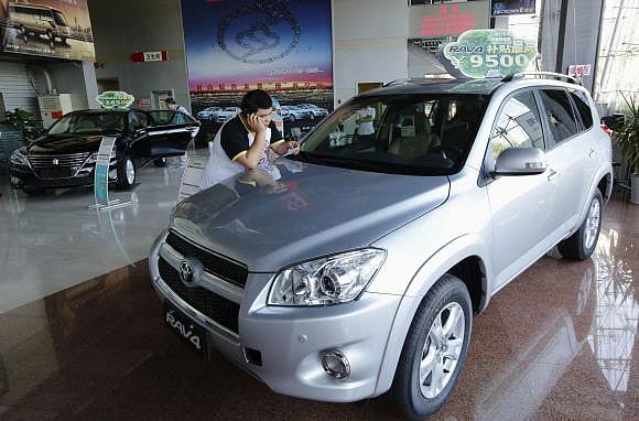 A man uses a mobile phone at a showroom of Toyota Motor in Beijing on 2 July 2013. Photo: Reuters