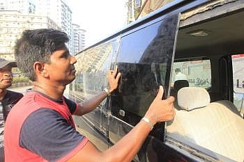 A man is seen removing tinted glass from a microbus at Banglamotor in the capital. Photo: Prothom Alo