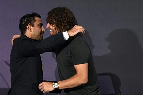 Barcelona's midfielder Carles Puyol (R) is congratulated by Barcelona's midfielder Xavi Hernandez during a farewell press conference at Camp Nou stadium in Barcelona on 15 May 2014. Photo: AFP