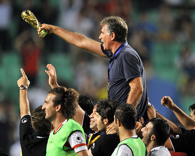Iran's head coach Carlos Queiroz (top), holding a mock trophy, celebrates with his players after their World Cup Asian qualifier football match against South Korea in Ulsan, some 300 km southeast of Seoul, on June 18, 2013. Iran won the match 1-0. AFP