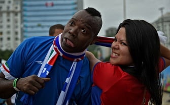 A man depicting Italy's forward Mario Balotelli jokes with a Italian fan during the live projection of the Group D match between Italy and Costa Rica in a Rio de Janeiro's beach on June 20, 2014 during the 2014 FIFA World Cup in Brazil. AFP