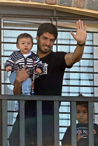 Uruguay's striker Luis Suarez, banned from football for four months after biting an opponent at the World Cup, holds his children Benjamin and Delfina as he greets fans from his mother's home in Lagomar, in the department of Canelones, near Montevideo, on June 27, 2014. AFP