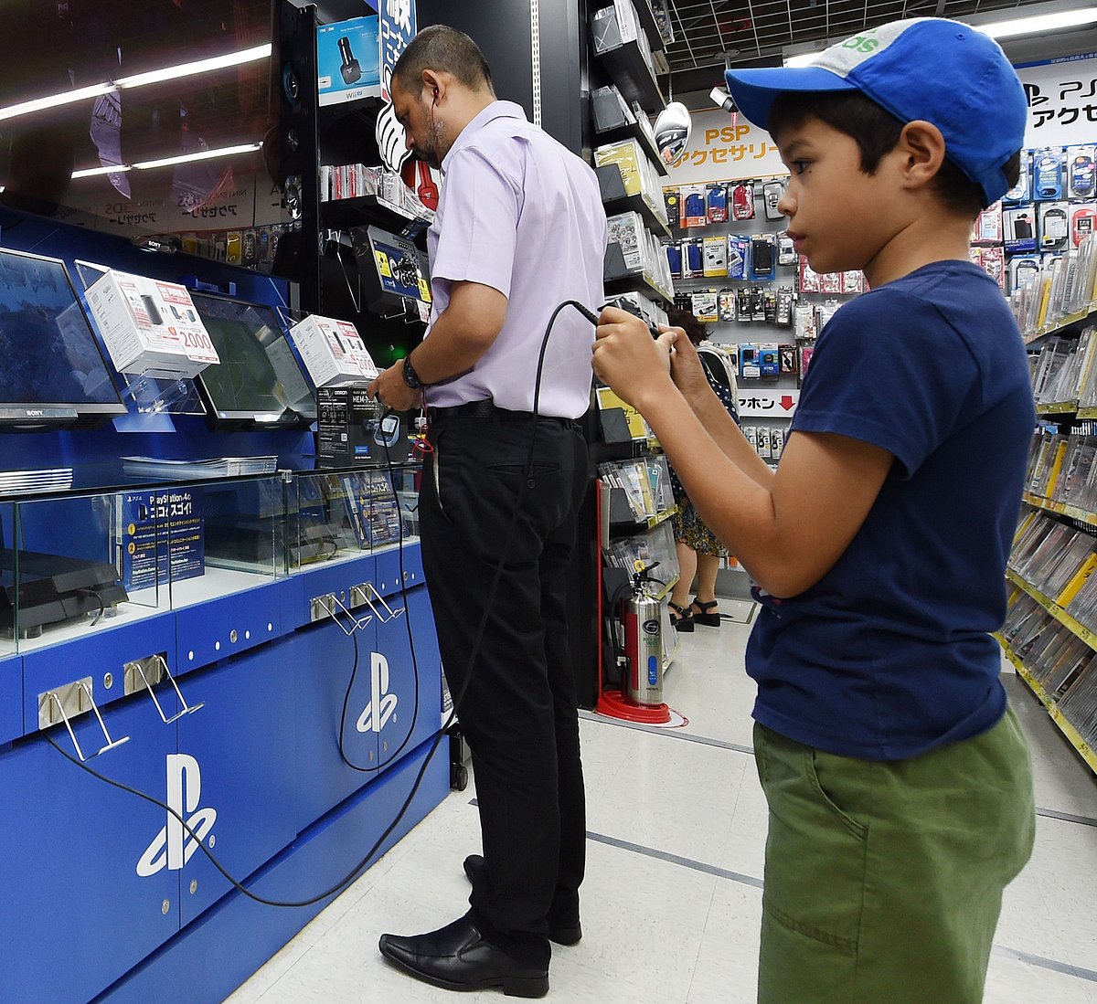 Customers play Sony's video game console PlayStation 4 at an electronics store in Tokyo on August 13, 2014. Photo: AFP