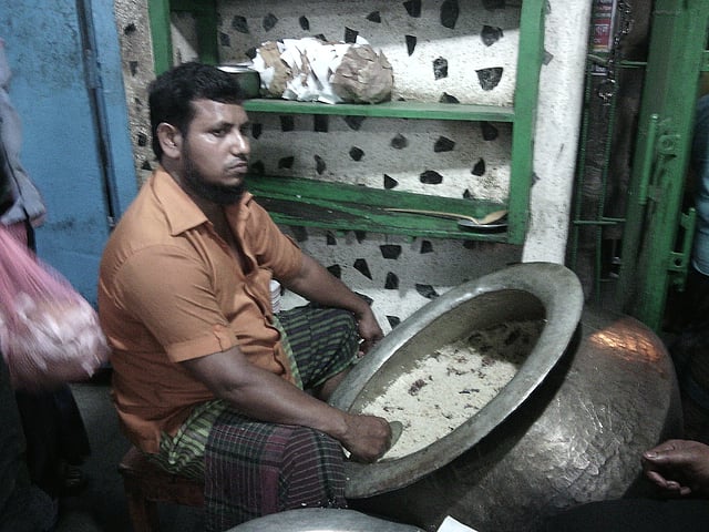 A restaurant worker, who serves food at flagship outlet of Haji Biriyani  on Alauddin road at Najirabazar of Old Dhaka, sits in front of a Biriyani food pot.