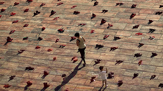 A woman and a child walk amidst an art installation of 745 pairs of female red shoes, put on display by Mexican visual artist Elina Chauvet to protest against gender violence and femicide. Photo: Reuters