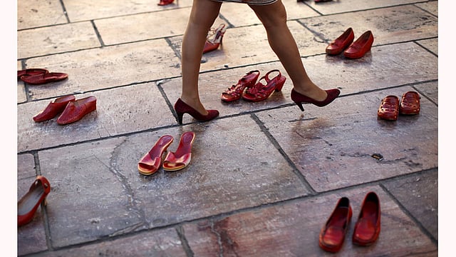 A woman walks in an art installation of 745 pairs of female red shoes put on display by Mexican visual artist Elina Chauvet to protest against gender violence and femicide. Photo: Reuters