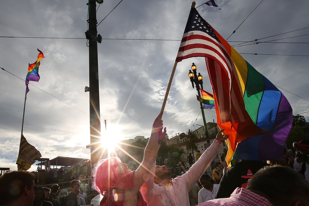 A woman helps Francisco Pavon, center, wave a rainbow pride flag and an American flag during a gay pride celebration on June 27, 2015 in San Francisco, California. Photo: AFP