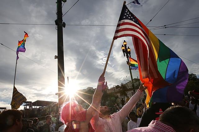 A woman helps Francisco Pavon, center, wave a rainbow pride flag and an American flag during a gay pride celebration on June 27, 2015 in San Francisco, California. Photo: AFP