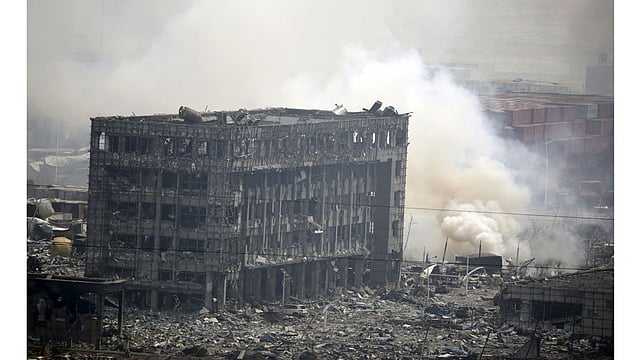 Smoke rises next to a damaged building at the site of the explosions at the Binhai new district in Tianjin, China, August 14, 2015. Photo: Reuters