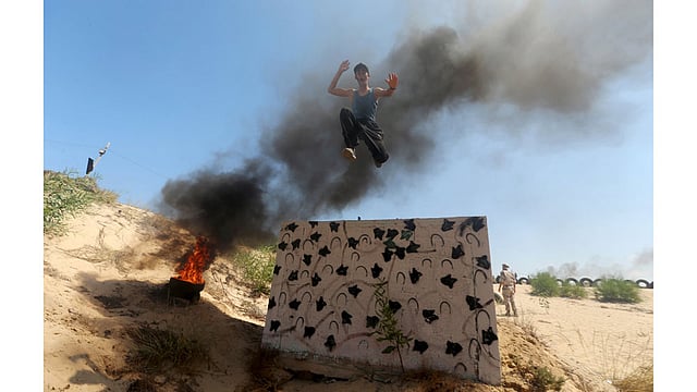 A young Palestinian jumps from the top of a wall during a military-style exercise at a summer camp organized by Islamic Jihad movement, in Khan Younis in the southern Gaza Strip, August 13, 2015. Photo: Reuters