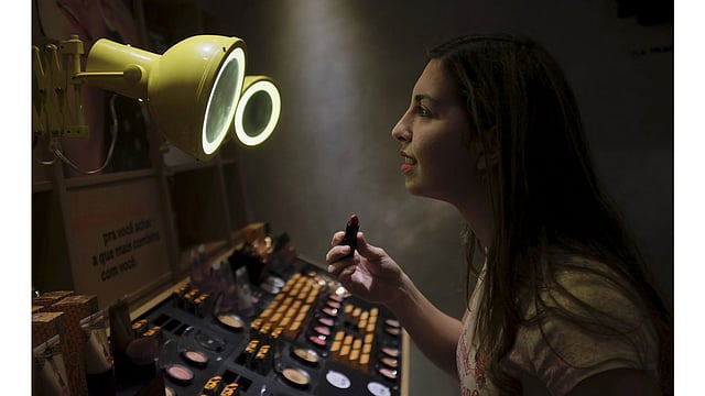 A woman checks lipstick applied on her lip, inside of a cosmetics shop in Sao Paulo, Brazil August 13, 2015. Photo: Reuters