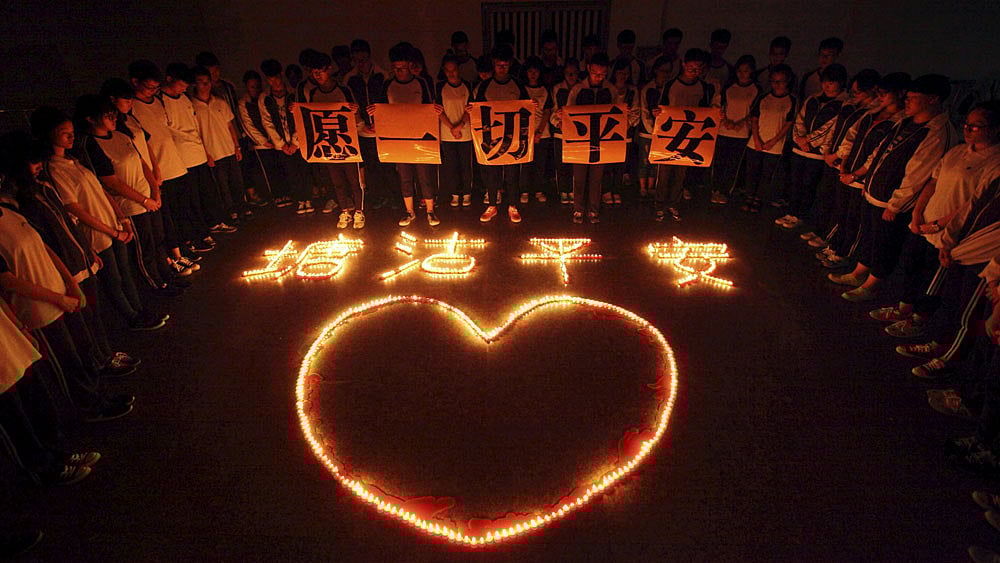 Students and teachers stand around lighted candles for victims of the explosions in Tianjin on Wednesday night, at a school in Zhuji, Zhejiang province, China, August 13, 2015. Photo: Reuters