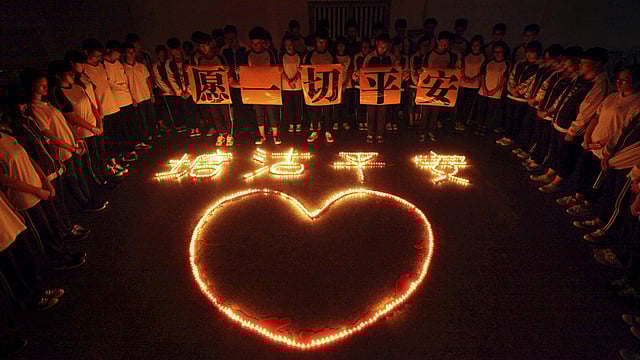 Students and teachers stand around lighted candles for victims of the explosions in Tianjin on Wednesday night, at a school in Zhuji, Zhejiang province, China, August 13, 2015. Photo: Reuters