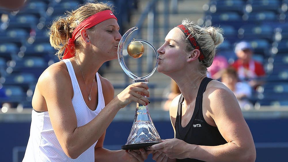 Mattek-Sands (black top) of the United States and Lucie Safarova of the Czech Republic kiss the doubles championship trophy during the doubles final on 7 day of Rogers Cup on 16 August in Toronto, Canada. Photo: AFP
