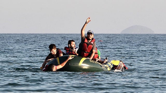 Syrian migrants try to make it to shore in their half-sunk dinghy as they arrive on the Greek island of Kos, on August 17, 2015. Photo: AFP