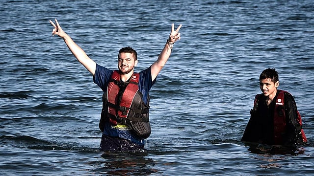 A Syrian migrant flashes the V-sign for victory after swimming to the shores of the Greek island of Kos from a half-sunk small dinghy on August 17, 2015. Photo: AFP