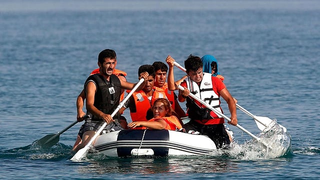 Exhausted Iranian migrants paddle an engineless dinghy as they approach the Greek island of Kos August 15, 2015. Photo: Reuters
