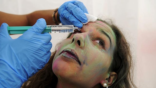 A member of Red Cross cleans the eye of a reveller during the Holi Party Festival at the Niemeyer Center in Aviles, northern Spain, August 29, 2015. Photo: Reuters