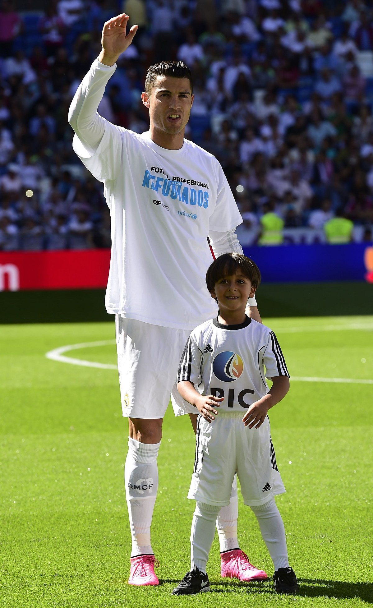 Real Madrid and Portuguese forward Cristiano Ronaldo (L) poses with Zaid, son of Osama Abdul Mohsen (C), the Syrian refugee who made world headlines when a Hungarian journalist tripped him over as he fled, before the Spanish league football match Real Madrid CF vs Granada FC at the Santiago Bernabeu stadium in Madrid on Spetember 19, 2015. AFP