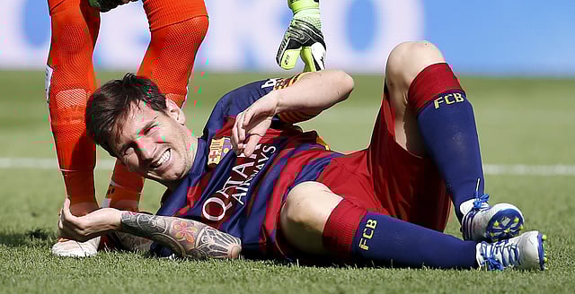 Barcelona's Lionel Messi grimaces as he lies on the pitch after injuring his left knee during their Spanish first division soccer match against Las Palmas at Camp Nou stadium in Barcelona, Spain, September 26, 2015. Photo: Reuters