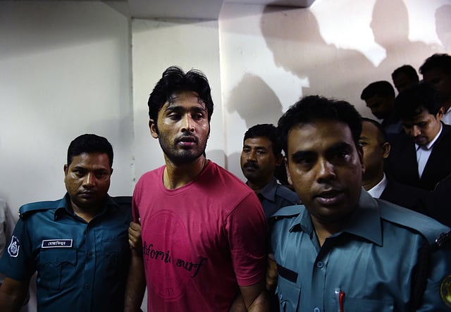 Bangladeshi security personnel escort fugitive cricketer Shahadat Hossain (C) after he surrendered in Dhaka on 5 October, 2015. Hossain was remanded in jail on 5 October shortly after he surrendered to a court over allegations of beating his 11-year-old maid, his lawyer said. AFP
