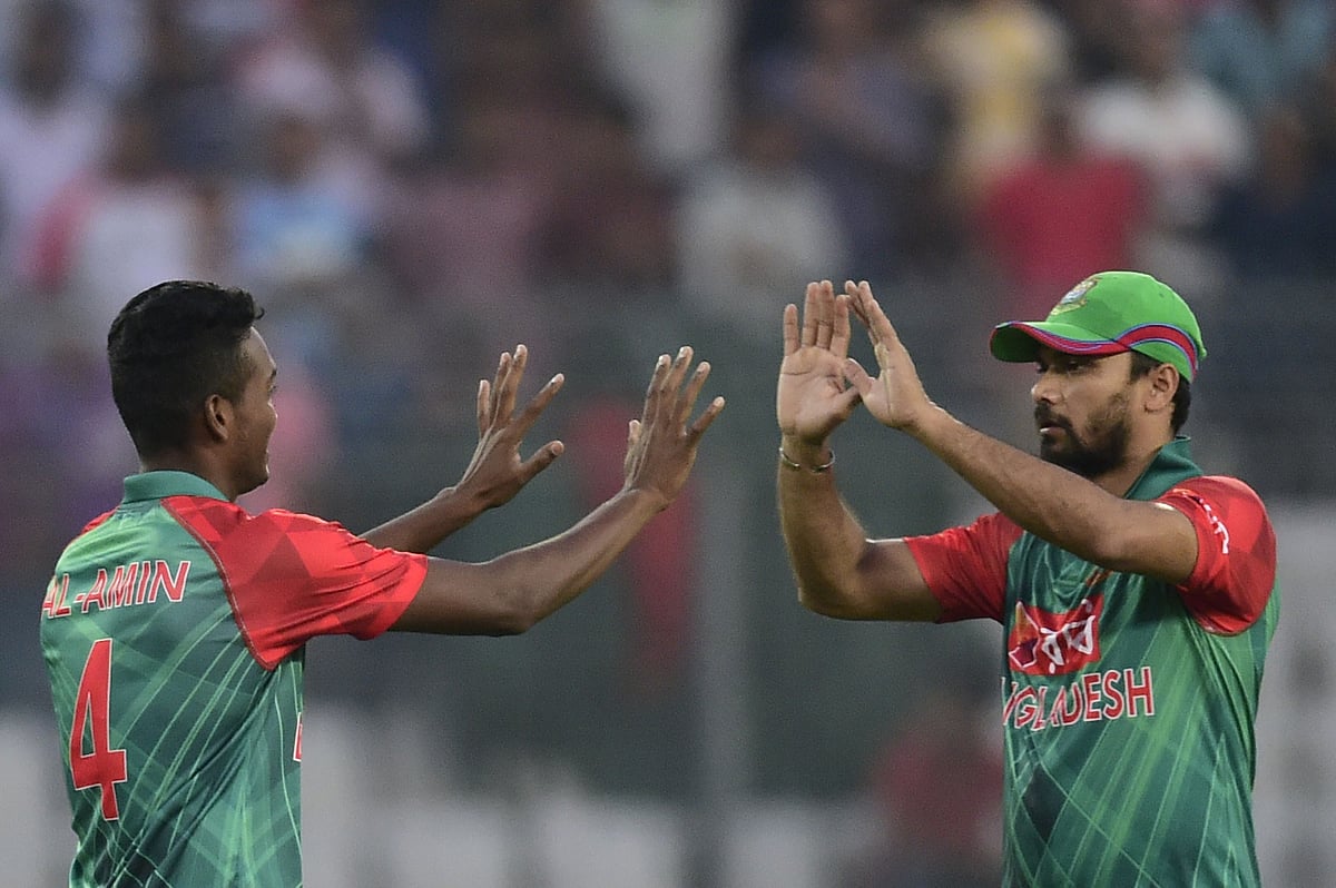 Bangladesh cricketer Al-Amin Hossain (L) celebrates with captain Mashrafe Bin Mortaza after the dismissal of Zimbabwe cricketer Regis Chakabva during the first T20 cricket match between Bangladesh and Zimbabwe at the Sher-e Bangla National Stadium in Dhaka on November 13, 2015. AFP