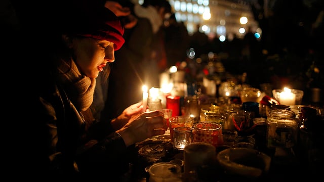 A woman lights a candle as people gather on the Place de la Republique square to pay tribute to the victims of last year’s shooting at the French satirical newspaper Charlie Hebdo, in Paris, France, January 7, 2016. Photo: Reuters