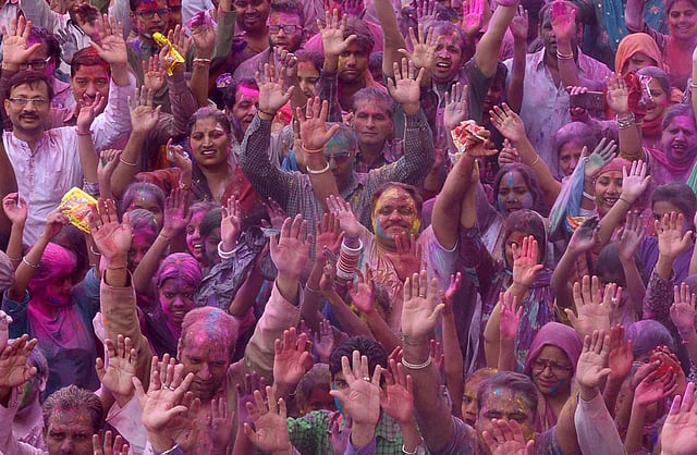Indian devotees covered with coloured powder pose for a photograph during Holi celebrations at the Durgiayana Temple in Amritsar. Photo: AFP