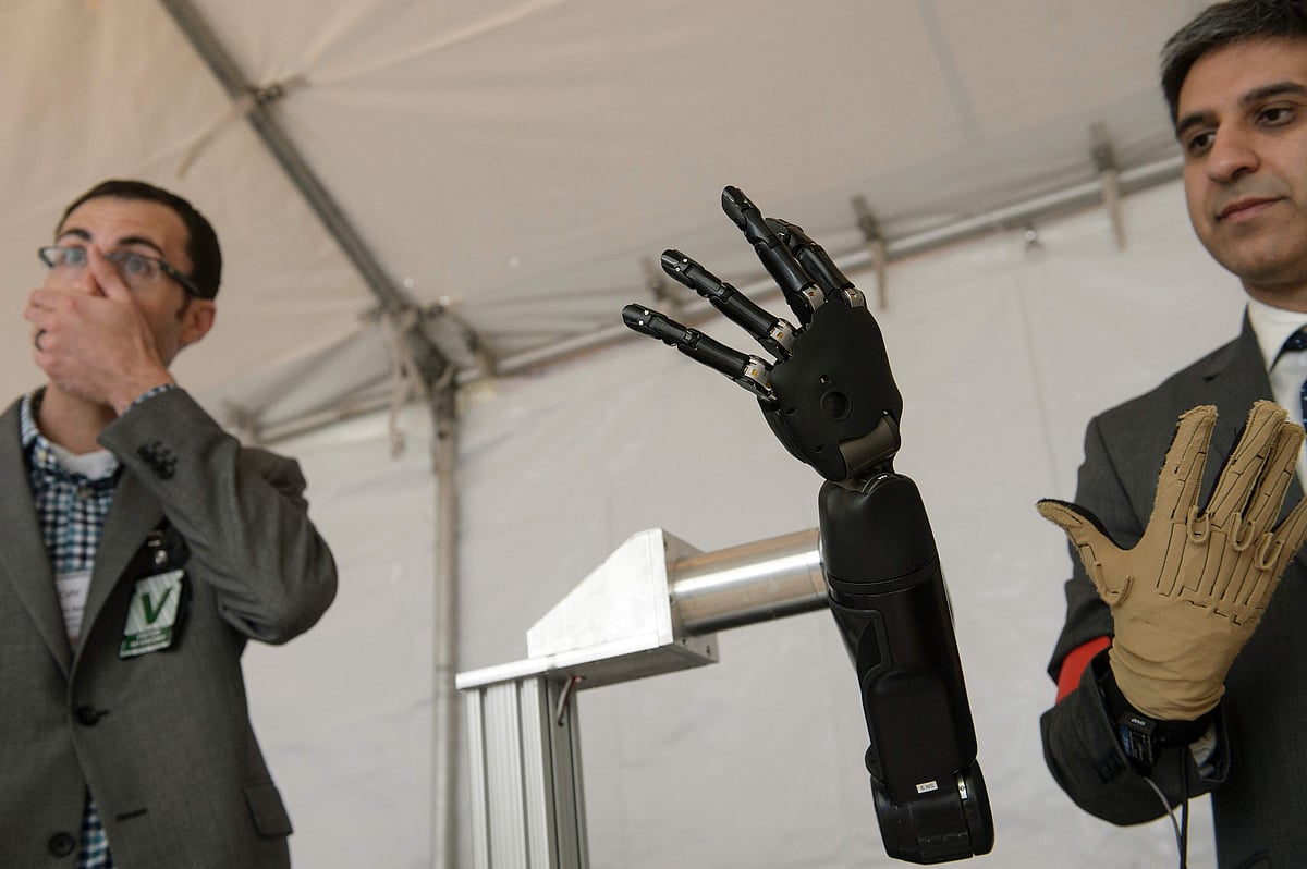 Exhibitors from Johns Hopkins Applied Physics Laboratory stand with a robotic hand during the Defense Advanced Research Projects Agency (DARPA) Demo Day at The Pentagon on 11 May in Washington, DC. Photo: AFP