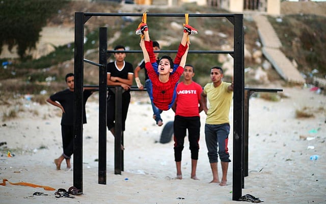 Palestinian boy Mohamad al-Sheikh, 12, who is nicknamed `Spiderman` and hopes to break the Guinness world records with his bizarre feats of contortion, demonstrates acrobatics skills on a beach in Gaza City June 2, 2016. Photo: Reuters