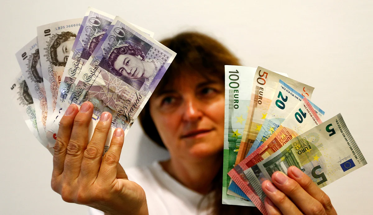 An employee holds British pounds and Euro banknotes in a bank at the main train station in Munich. Reuters
