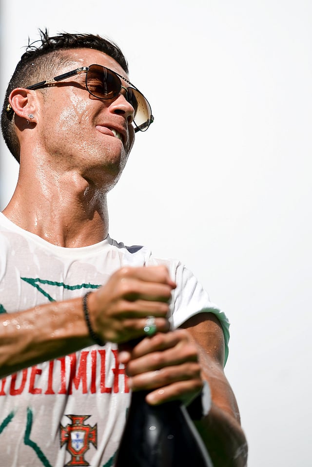 Portugal's forward Cristiano Ronaldo tries to open a big bottle of beer as he celebrates with teammates at Alameda square in Lisbon on July 11, 2016 where thousands of supporters welcome them with scarfs and flags to celebrate their victory over France in their Euro 2016 final played yesterday. Photo: AFP