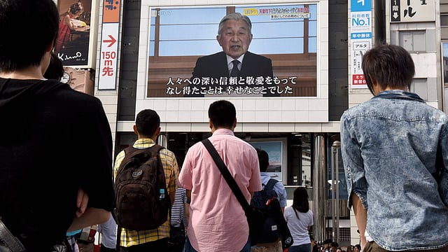 People look at a big video screen on the street as a speech by Japanese Emperor Akihito to the nation is televised in Tokyo on 8 August, 2016. Photo: AFP