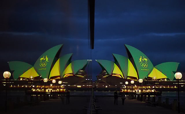 The Sydney Opera House is illuminated with the green and gold colours of the Australian Olympic team and reflected in a hotel window in Sydney, Australia, before the Olympics opening ceremony. Photo: Reuters