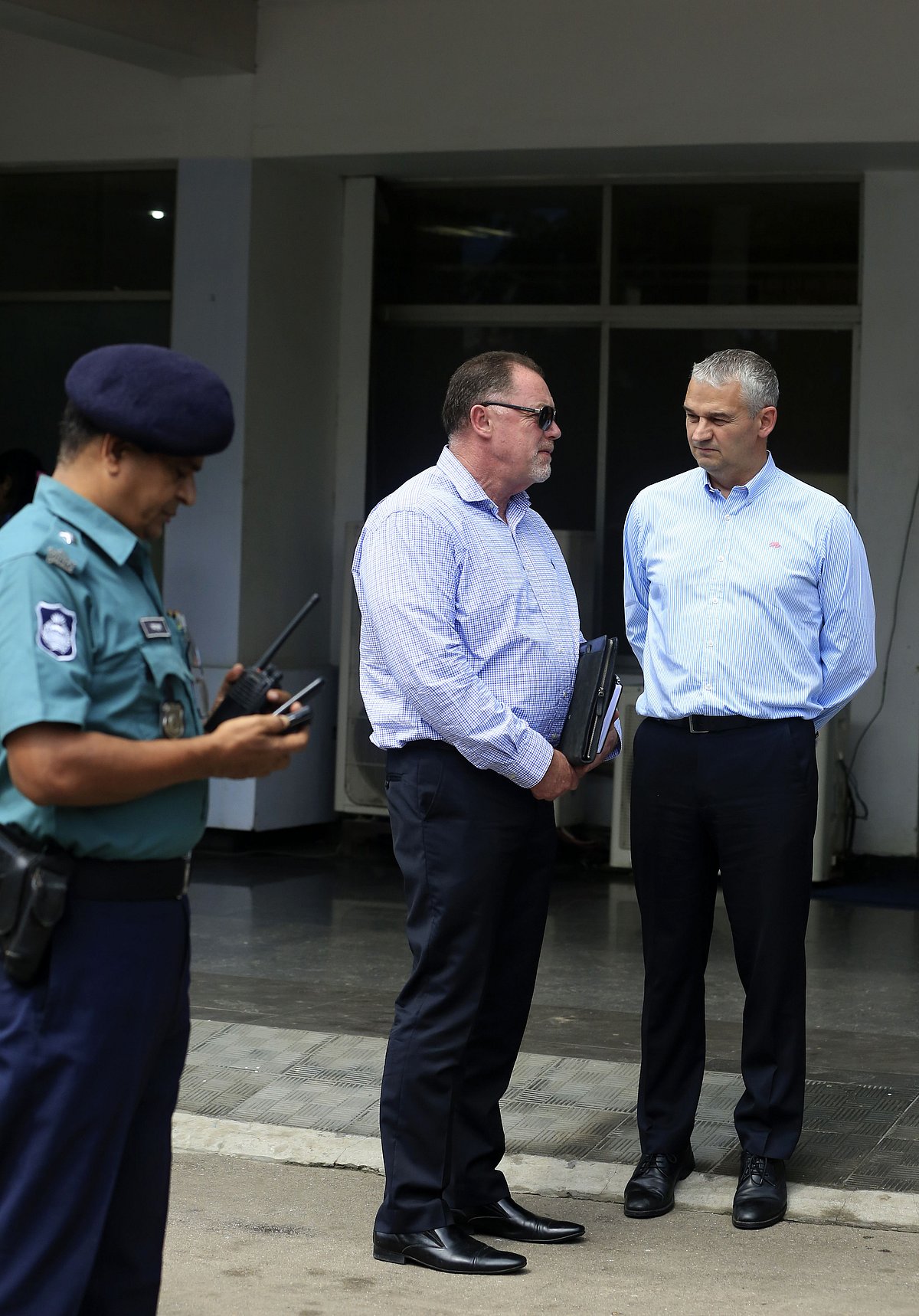 England Cricket Board (ECB) security advisor Reg Dickason (C) and Professional Cricketers Association(PCA) Chief Executive David Leatherdale (R) are watched by a Bangladeshi police official as they speak while standing at The Sher-e-Bangla Cricket Stadium at Mirpur in Dhaka on August 18, 2016. AFP