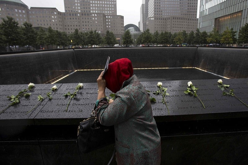 A woman places white roses at the National September 11 Memorial and Museum in Lower Manhattan in New York, September 10, 2015. REUTERS