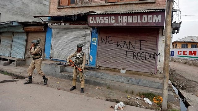 Policemen stand guard near a shop with its shutters sprayed with graffiti in Srinigar, India August 10, 2016. Photo: Reuters